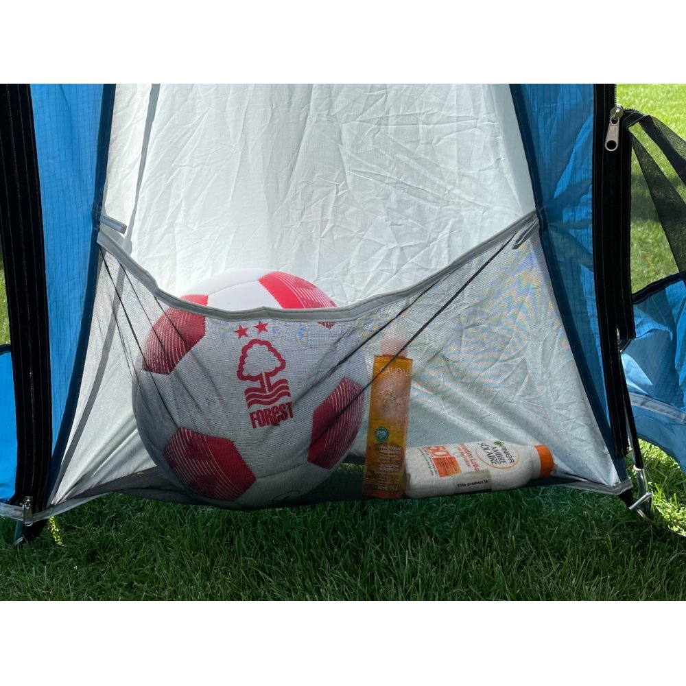 Mesh storage pocket in camper tent holding a football and sunscreen on grass