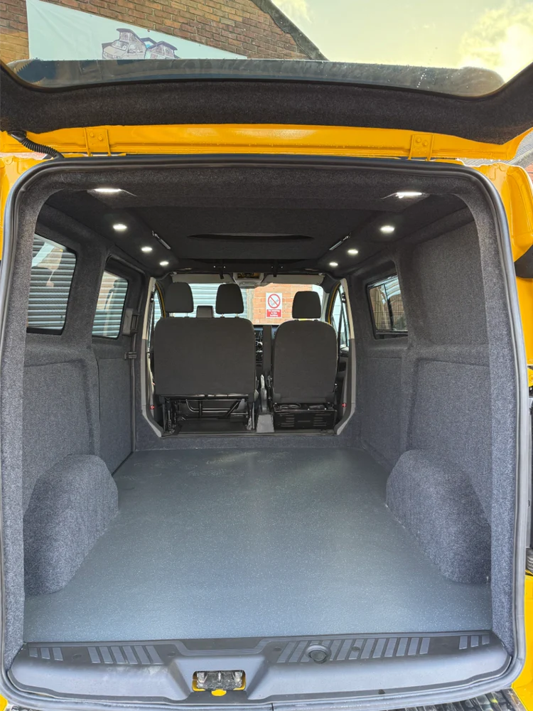 Empty yellow campervan interior with grey carpeted walls and LED ceiling lights