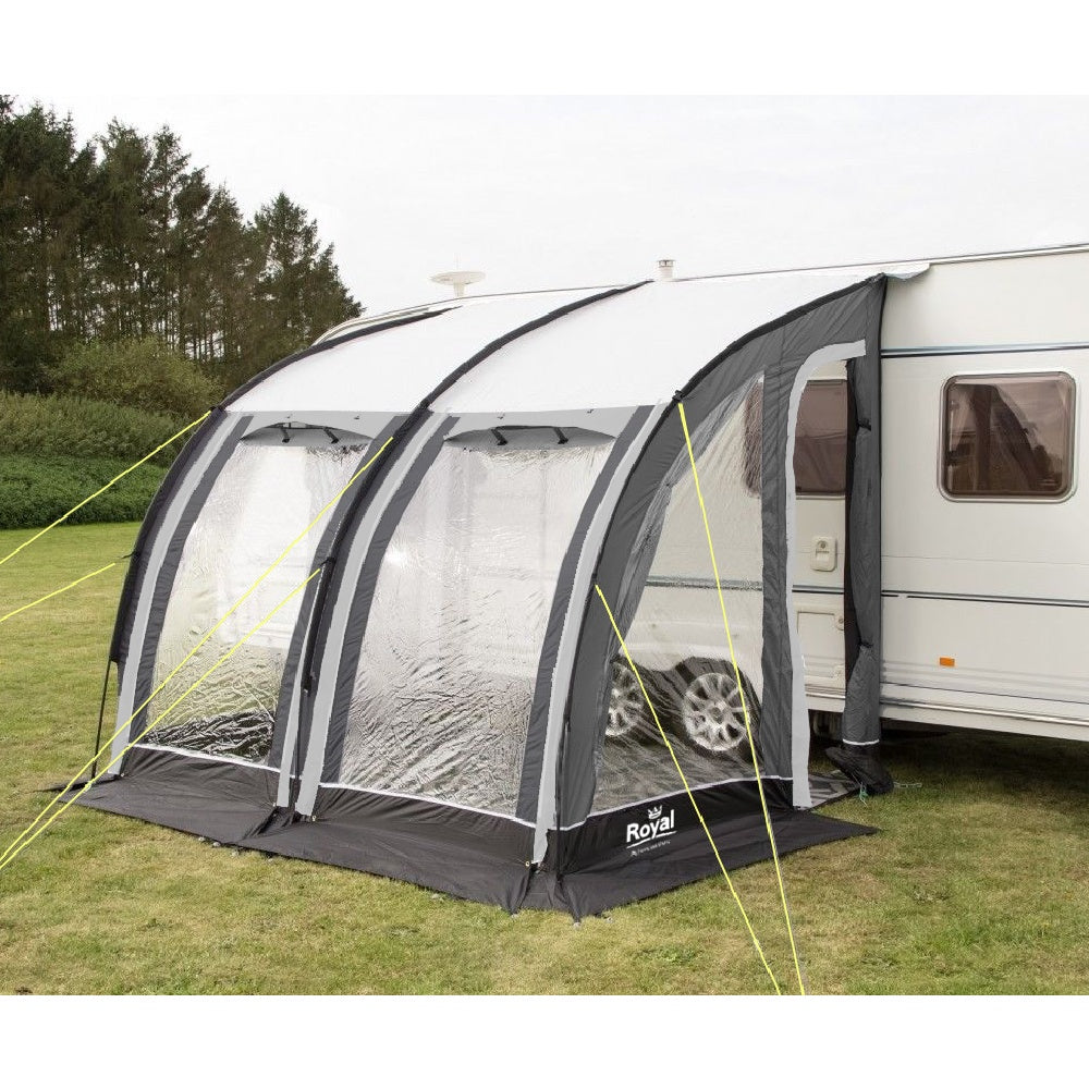 Caravan with attached inflatable awning tent on grassy campsite