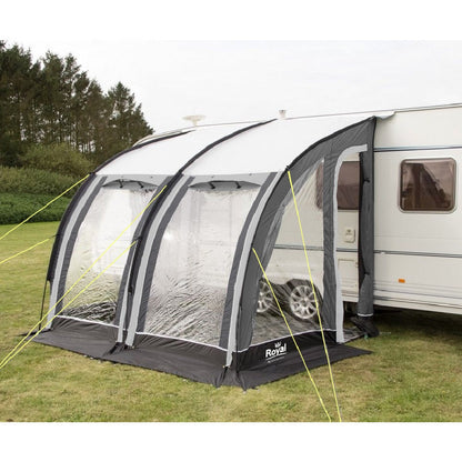 Caravan with attached inflatable awning tent on grassy campsite