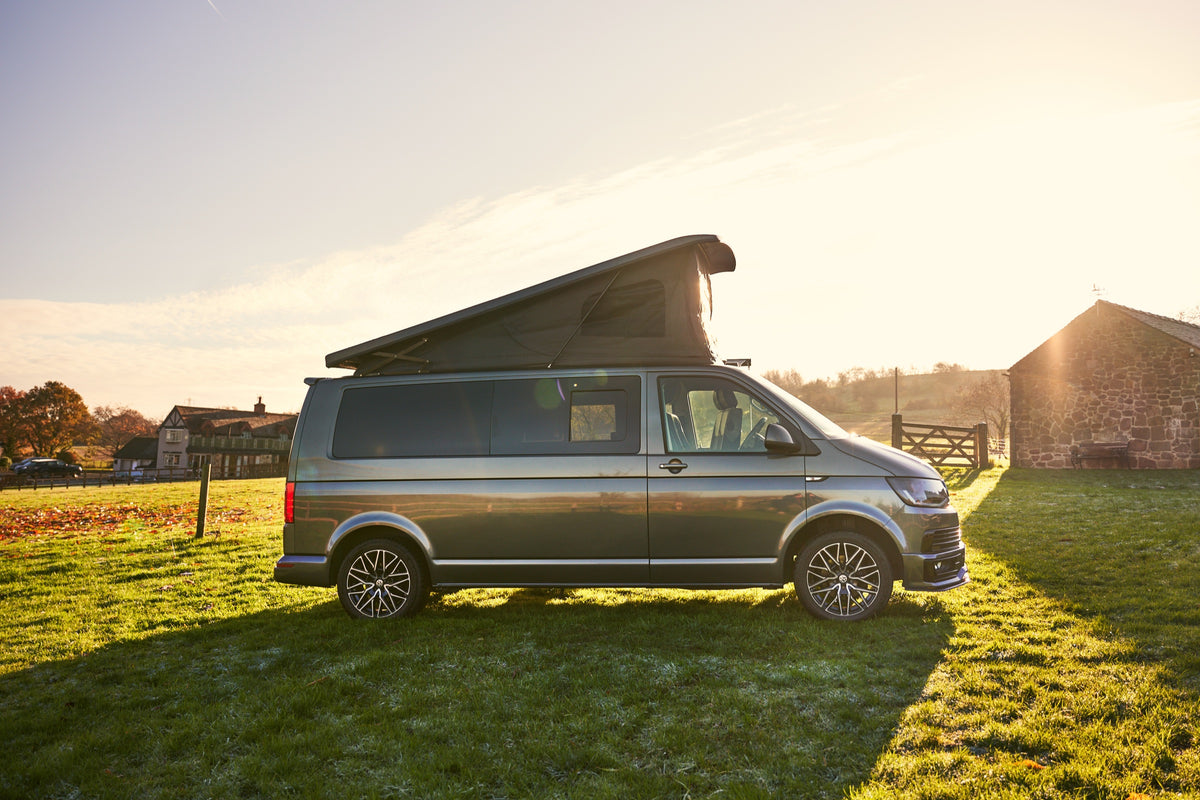 Grey Relive campervan with raised pop-top roof in a sunlit field